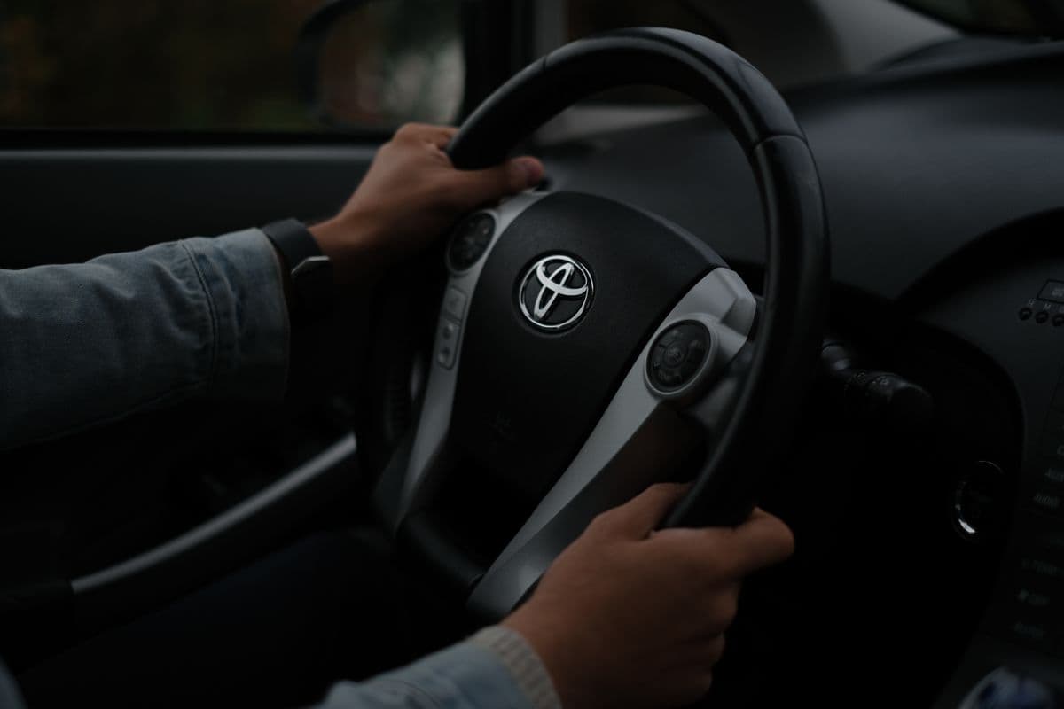 Mãos de um condutor a segurar o volante de um veí­culo, com atenção na estrada
