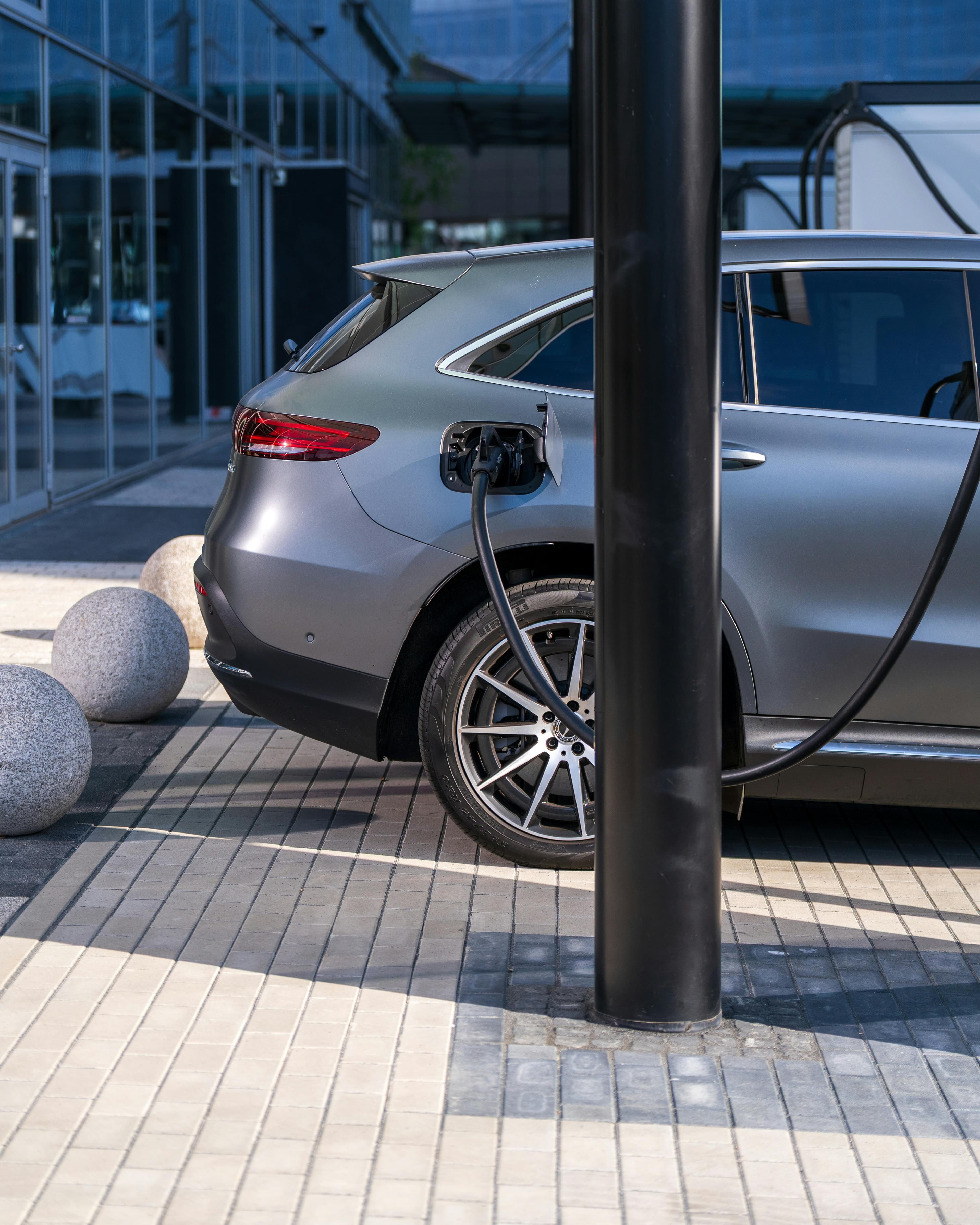 Posto de combustível com preços elevados ao lado de um carro elétrico a carregar